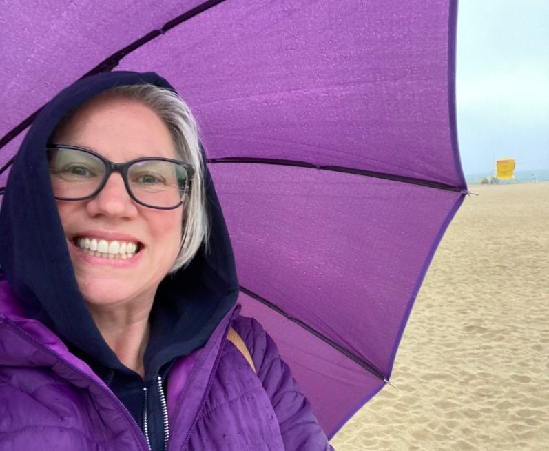A woman at the helm of a boat, smiling for the camera.